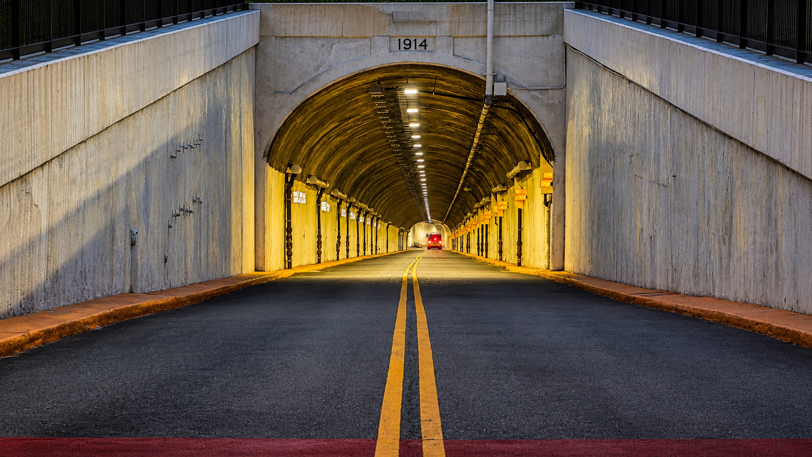 Bus approaching through a concrete tunnel at dusk
