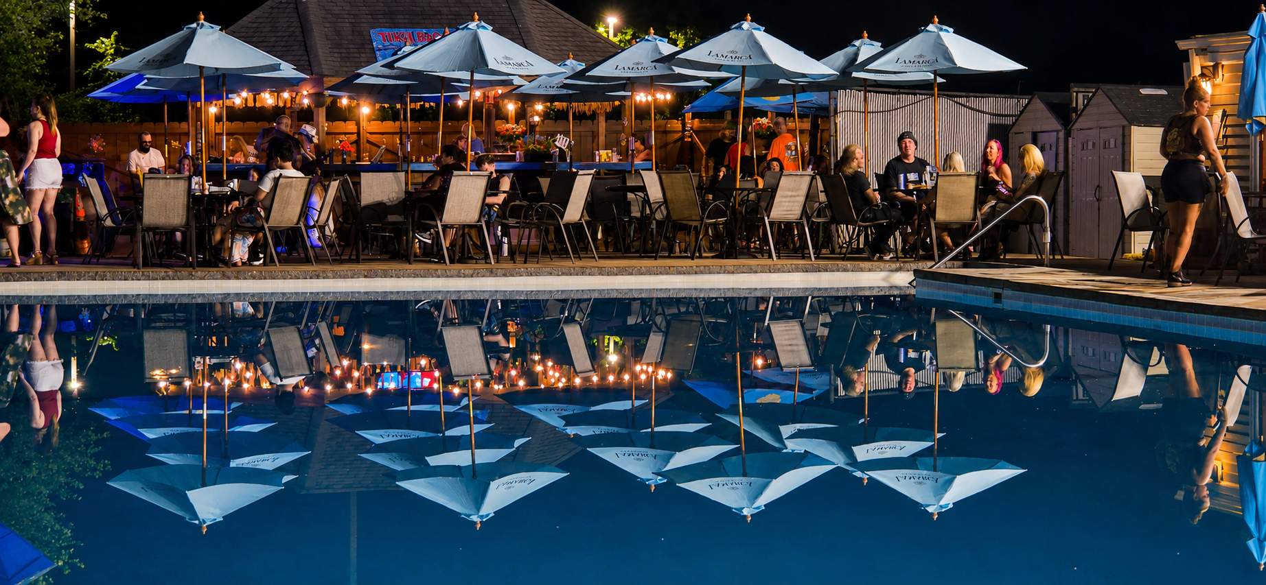 Poolside umbrellas reflected in water at night
