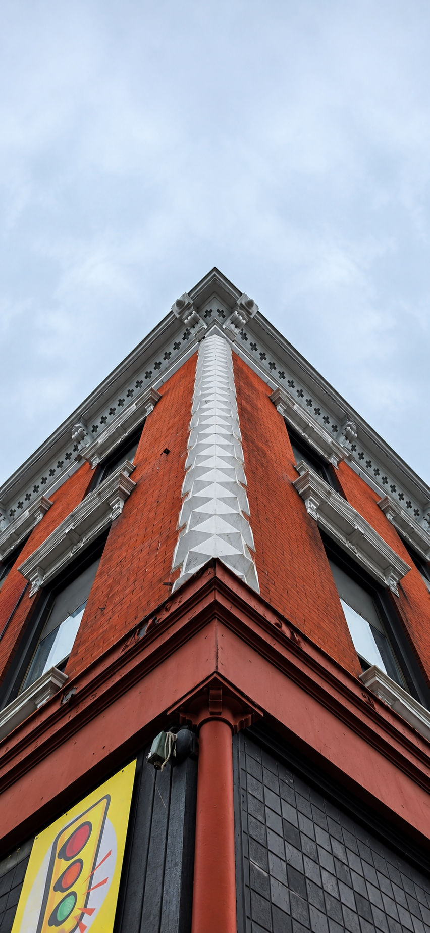Red brick corner building rising into a pale sky